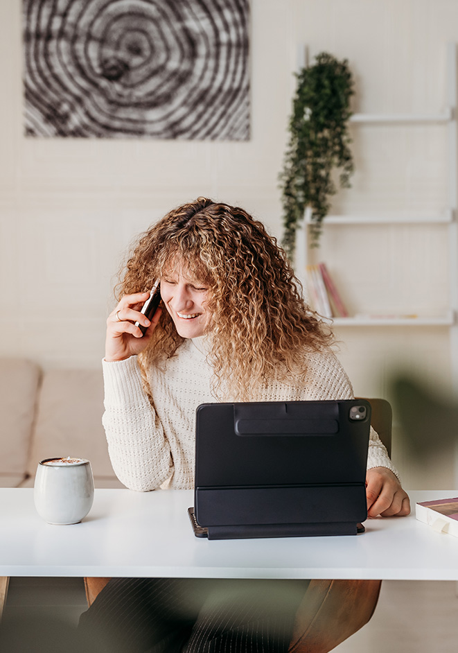 Lisa Turcanu telefoniert und arbeitet am Tablet am Schreibtisch.